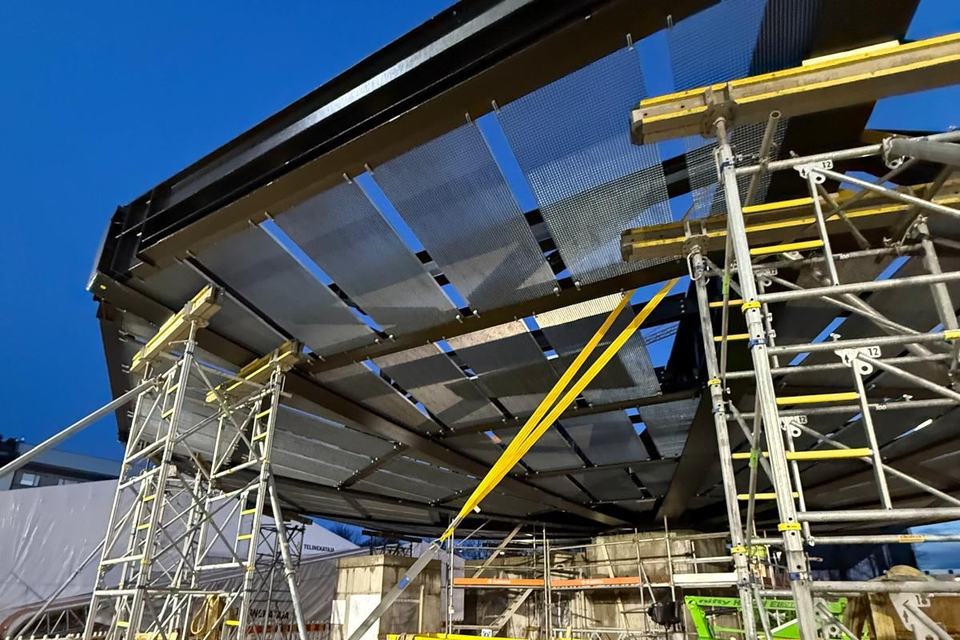 Curved steel roof structure of the Atlas Pavilion supported on scaffolding towers
